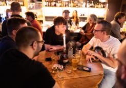 Leute sitzen in einer Bar um einen runden Tisch.