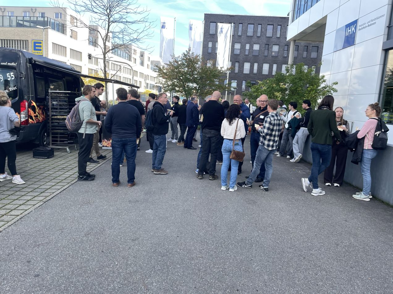 Leute stehen vor einem Gebäude bei der Mittagspause beim Open KI Bodensee Barcamp